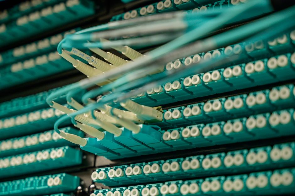 Vista detallada de cables de fibra óptica conectados a un rack de servidores, mostrando tecnología moderna.