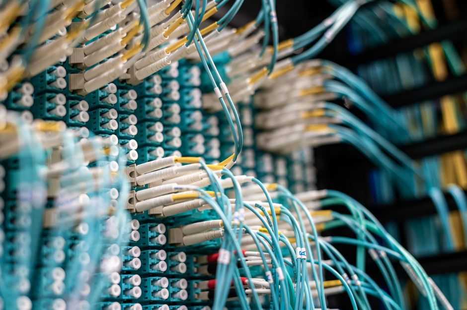 Vista inferior de cables azules conectados a conectores blancos en un rack de datos