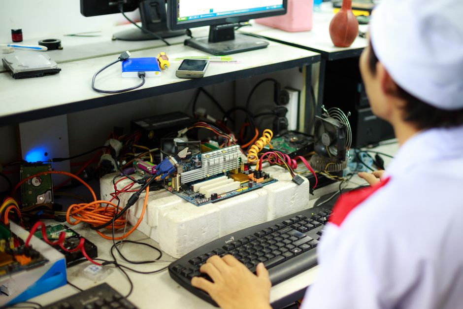 Técnico en uniforme de laboratorio trabajando en componentes y cableado de un equipo